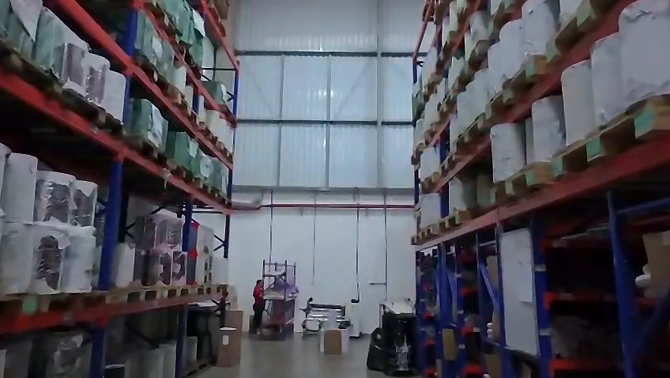 Interior do galpão com estrutura porta-pallet e a marca Grupo Kairós na parede